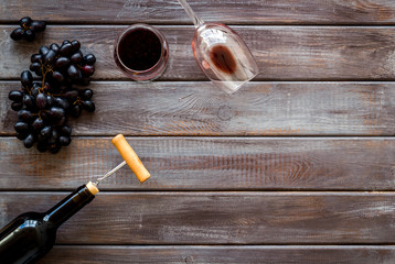 Red wine bottle near wineglass on dark wooden background top view copy space