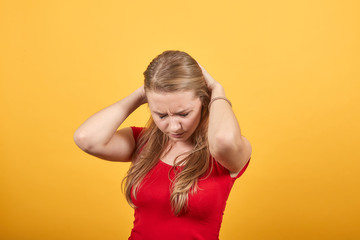 young blonde girl in red t-shirt over isolated orange background shows emotions