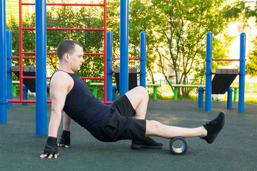 man in black gloves, outdoors, doing sports and doing roller massage, calf muscle