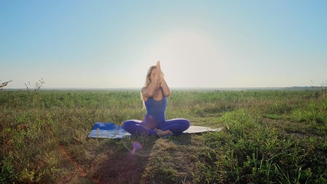 Woman is doing yoga. Dawn, green field.