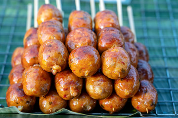 Grilled Thai sausage at street food market in Thailand, closeup. Traditional Thai sausage with pork and rice, delicious street food
