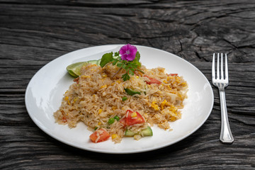 Fried rice with shrimps and vegetables in a white dish on an old wooden table, close up . Thai food , Thai cuisine