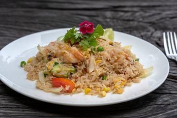 Fried rice with shrimps and vegetables in a white dish on an old wooden table, close up . Thai food , Thai cuisine