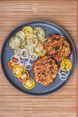 Chopped chicken cutlet with grilled vegetables lie on a plate. Grilled poultry and vegetables. Beautiful food. Food layout.