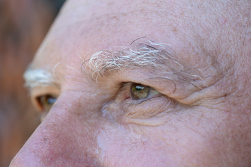 Closeup eye of caucasian old man. Portrait of old man outdoors. Caucasian male face background, close up eyes, macro