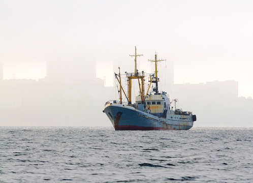 The ship on the roadstead against the city in the morning fog. Vladivostok. Russia.