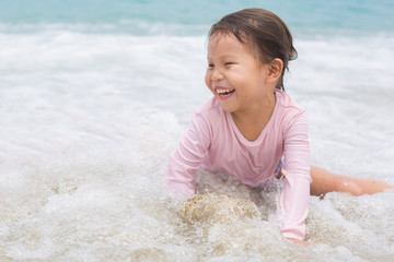 Happy active little girl playing and having fun on the beach sand.