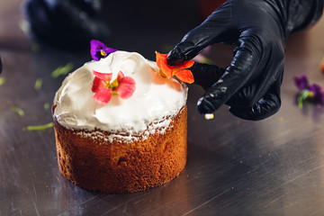 Confectioner decorates Easter cake with delicate flowers.