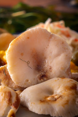 Salted mushrooms in a wooden plate on a background of fermented products. Close-up