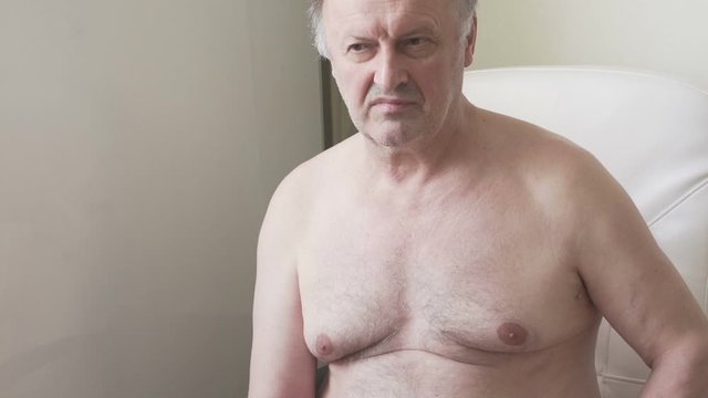 an elderly man sits without a shirt