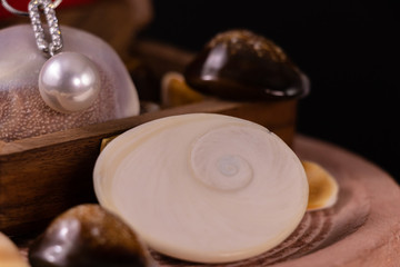 Close view of beautiful pearl necklace with spreaded seashells in wooden box on black background