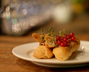 eclairs decorated with fresh berries on a white plate, handmade, culinary theme, close up
