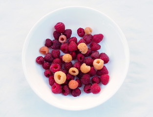 Red and yellow raspberry berries on a white plate