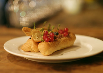 eclairs decorated with fresh berries on a white plate, handmade, culinary theme, close up