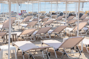 Sunbeds and parasols on morning, by the sea water. Beach in luxury resort near sea. Beautiful morning seascape. Tourist places. Typical mediterranean beach, a place holidays in summer, Greece