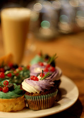 cupcake and eclairs on a plate next to latte coffee, warm colors, delicious desserts, close up