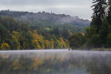 Nice misty fog on Vltava river with autumn foliage