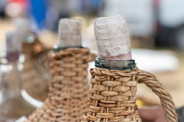 The stopper and the neck of a wicker bottle of wine in the background, closeup