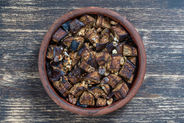 Baked eggplant with walnut, olive oil and spices on a plate on the wooden table. Vegetarian food. Close up