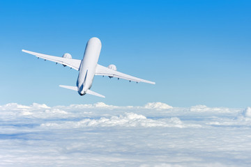 Fototapeta premium Samolot nabiera wysokości lecąc w oddali ponad chmurami, widok z tyłu.