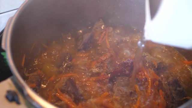 Boiling meat crots with carrots when cooking Plov traditional dish from Uzbekistan