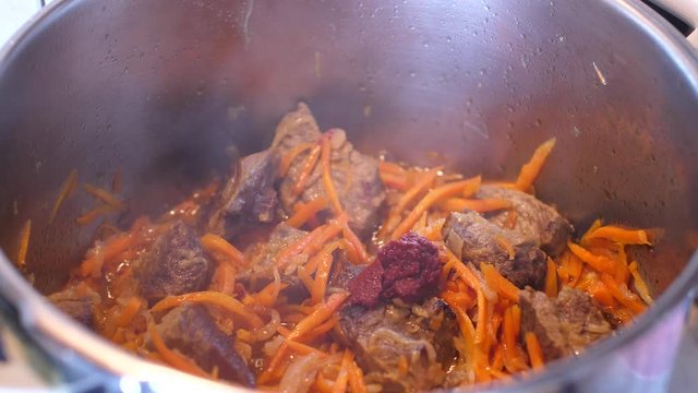 Adding spices to meat crots and carrots when cooking Plov traditional dish from Uzbekistan