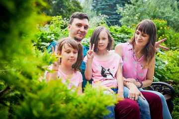 Fototapeta premium Family of four including father, mother and daughters in the Park on a summer day