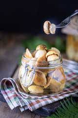Canned edible porcini mushrooms in a glass jar. Homemade pickled mushrooms