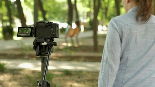 Woman set self timer on tripod mounted camera then takes a selfie. 