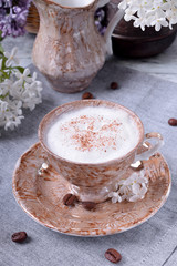 Freshly brewed coffee with a milky foam topped with cinnamon in a brown cup