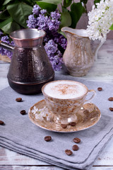 Freshly brewed coffee with a milky foam topped with cinnamon in a brown cup