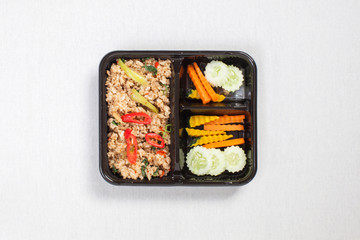Basil fried rice with minced pork, put in a black plastic box, put on a white tablecloth, food box, Spicy fried pork with basil leaves, Thai food.