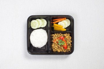 Pork with yellow curry paste and Rice put in black plastic box, put on a white tablecloth, food box, Thai food.