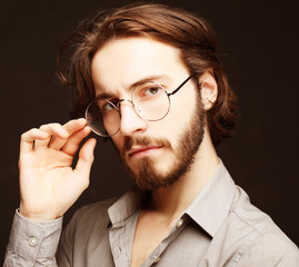 Young man wearing eyeglasses over black background.