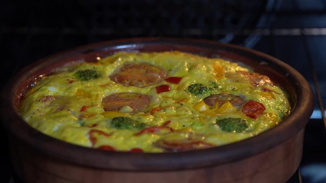 Ceramic bowl with vegetable frittata, simple vegetarian food. Frittata with egg, tomato, pepper, onion, broccoli and cheese , close up. Italian egg omelette in oven