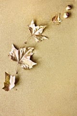 Autumn flat lay with painted golden leaves and copy-space on sparkling golden paper