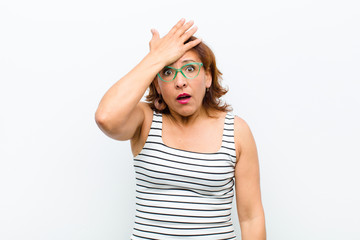 middle age pretty woman raising palm to forehead thinking oops, after making a stupid mistake or...