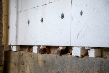 Insulation work of house walls with styrofoam sheets.