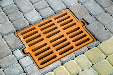 Old rusted metal gutter for rain water on the stone paved sidewalk.