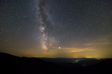 Night landscape of mountains with stars covered sky .