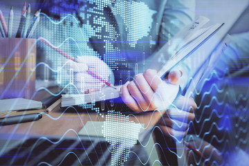 A woman hands writing information about stock market in notepad. Forex chart holograms in front. Concept of research. Multi exposure