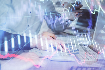 Multi exposure of chart with man typing on computer in office on background. Concept of hard work.