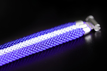 Beaded bracelet of three crocheted ropes on a dark background close up
