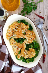 Baked cauliflower with greens on a wooden table. A beautiful cut of cauliflower. Healthy eating concept. The top view.