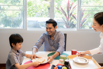 Asian family, father and son having breakfast together with mother in dining room, happy family...