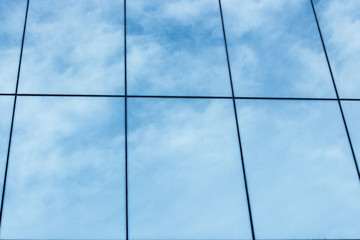 blue sky and clouds reflected in windows of modern building