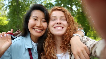 Slow motion portrait of happy young women friends taking selfie outdoors with shopping bags smiling looking at camera. Lifestyle and modern people concept. - Powered by Adobe