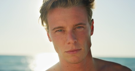 Portrait of young smiling man is happy to enjoy a summer vacation on a beach with a sea in a sunny day.