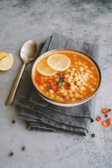 Chickpea lentil soup in bowl on gray background. Harira Moroccan soup. Comfortable food in the cold season