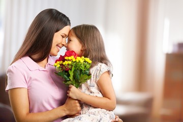 Fototapeta na wymiar Portrait of happy mother and daughter holding flowers